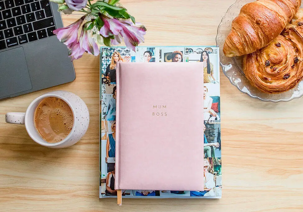 Coffee and Mum Boss notepad with croissants and laptop on a desk