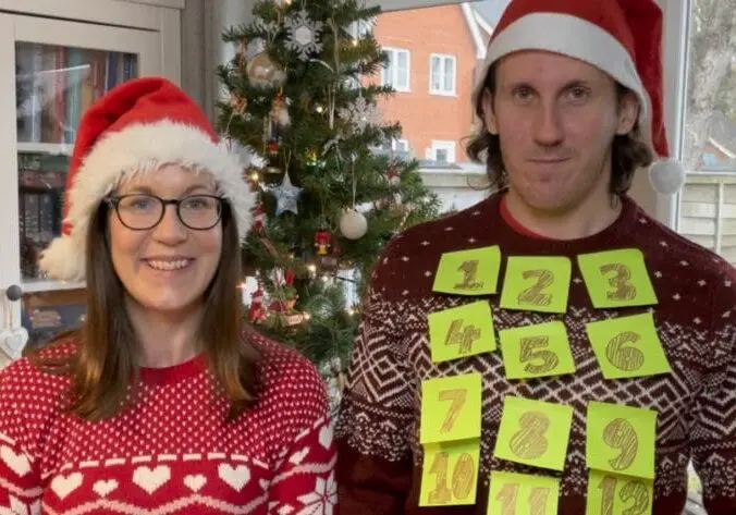 Jude and Chris in Christmas jumpers and hats smiling Thank you