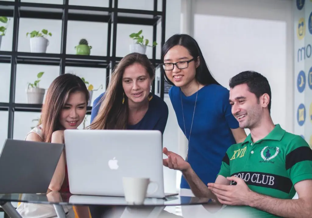 Three women and a man looking happy at a computer
