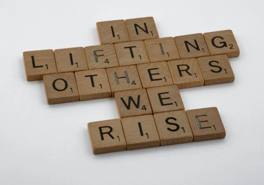 In Lifting Others We Rise made out of wooden scrabble tiles