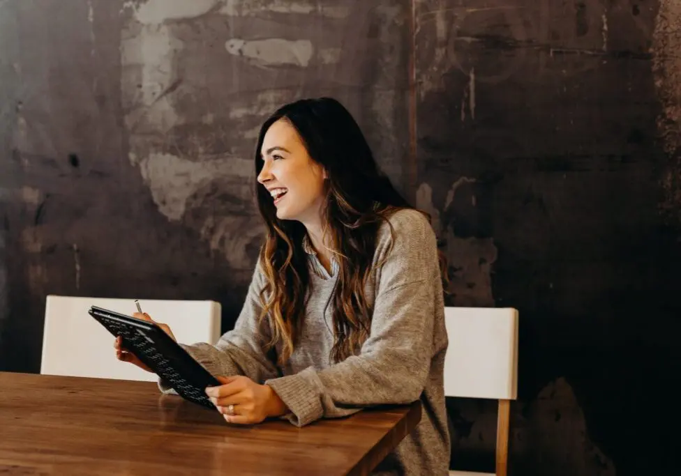 Woman laughing while holding a tablet device
