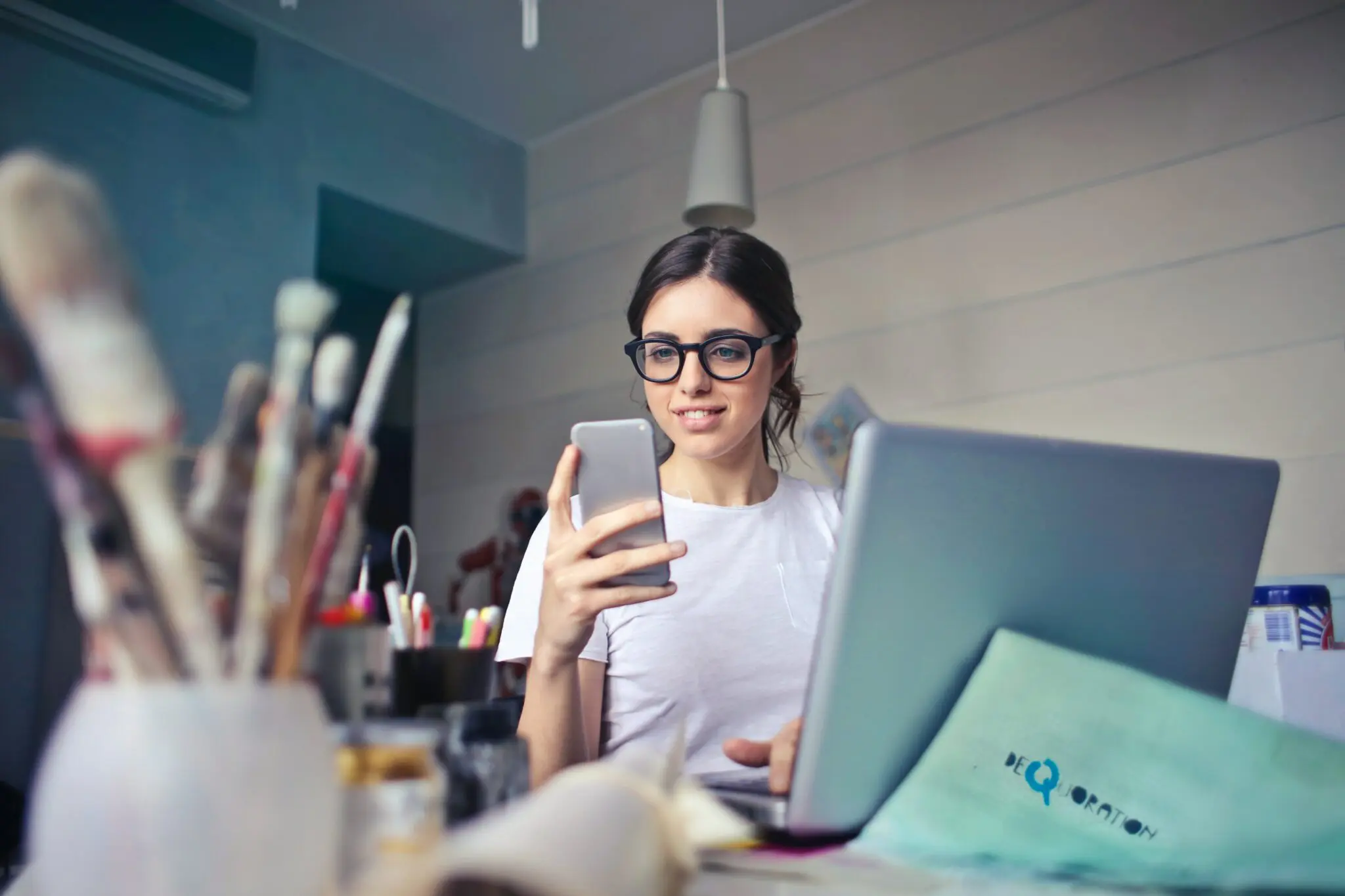 Woman with phone and laptop in an art studio