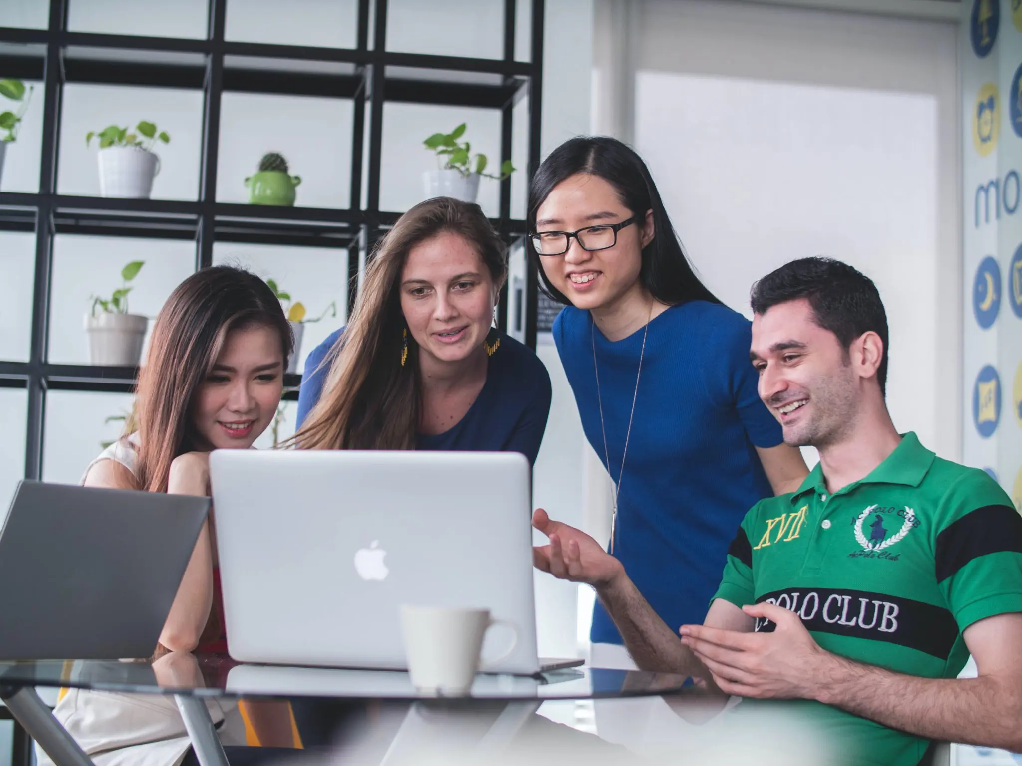 Three women and a man looking happy at a computer