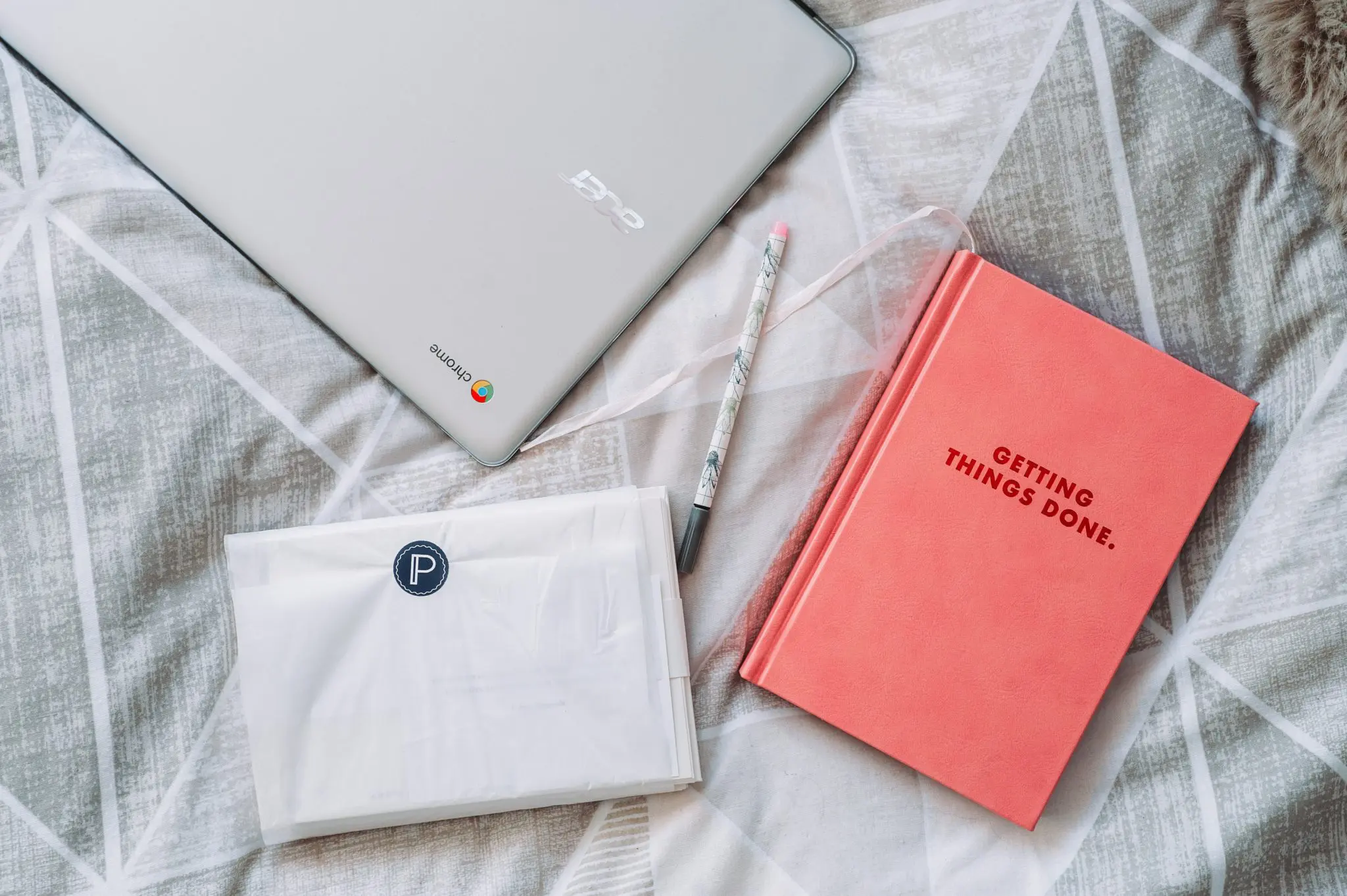 Laptop and notebook on bed of person trying to get more done