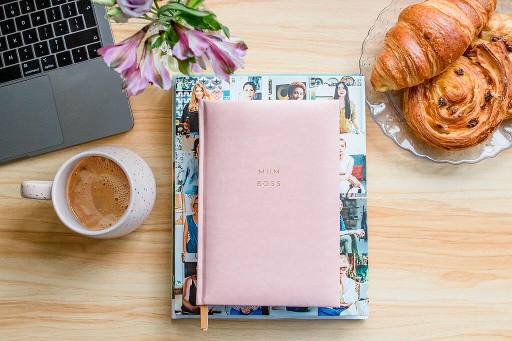 Coffee and Mum Boss notepad with croissants and laptop on a desk