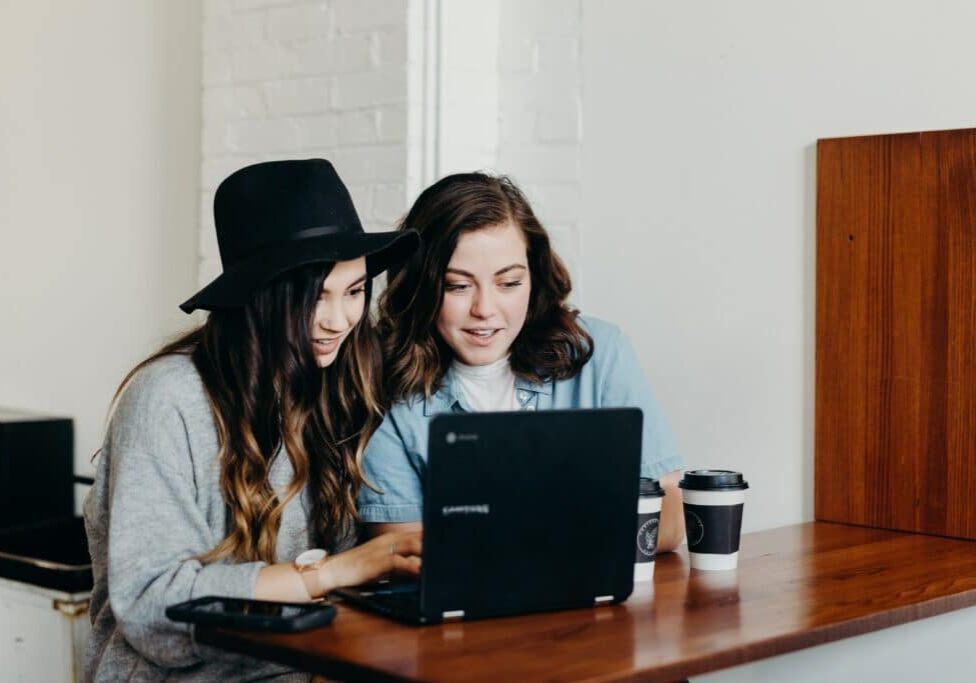 two women sitting at a laptop smiling