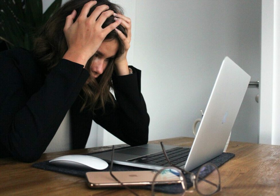 woman holding her head at a computer with a website tech headache