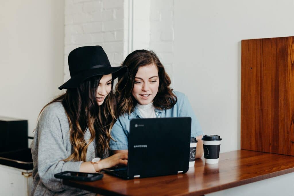 two women sitting at a laptop smiling