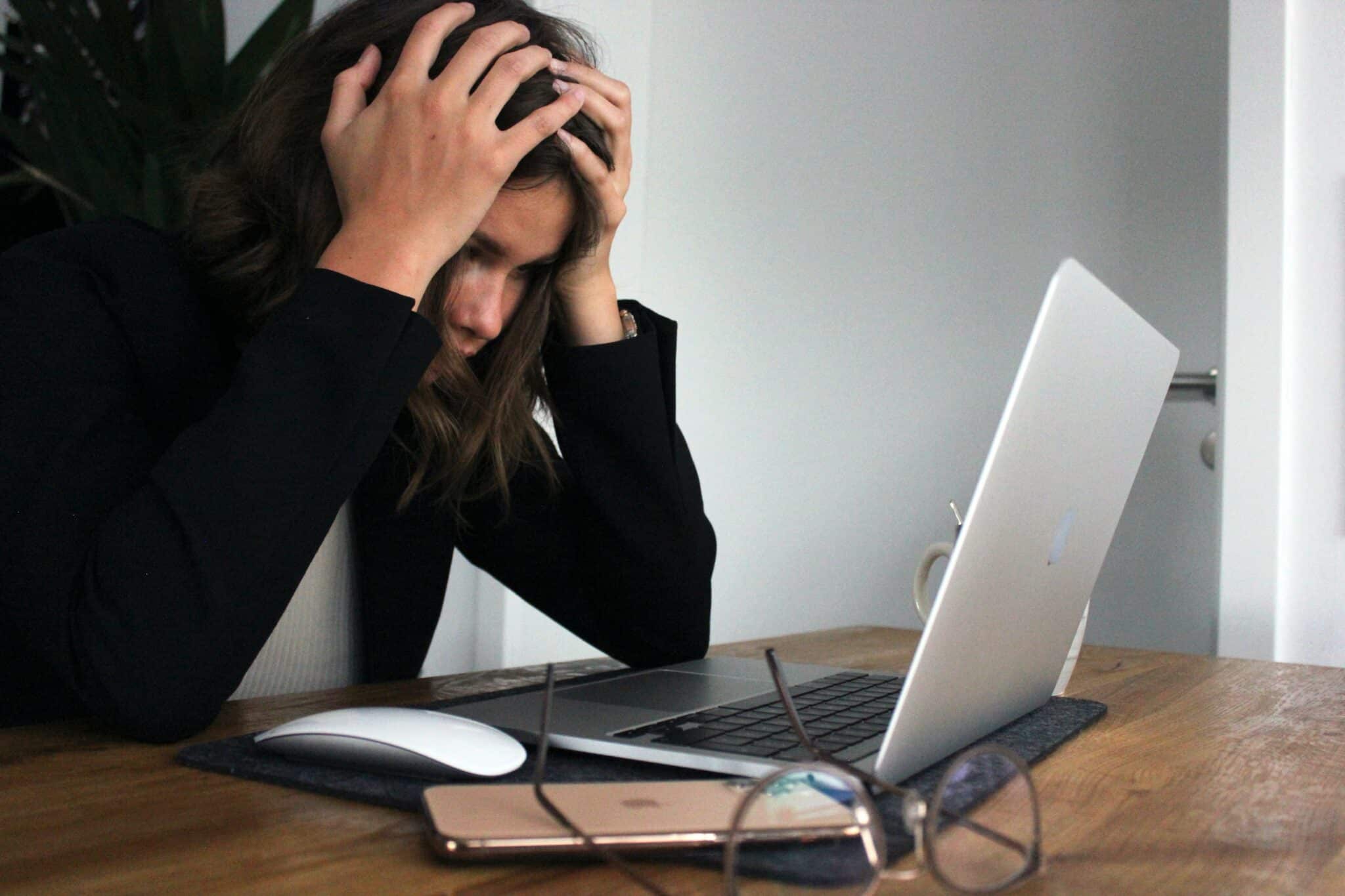 woman holding her head at a computer with a website tech headache