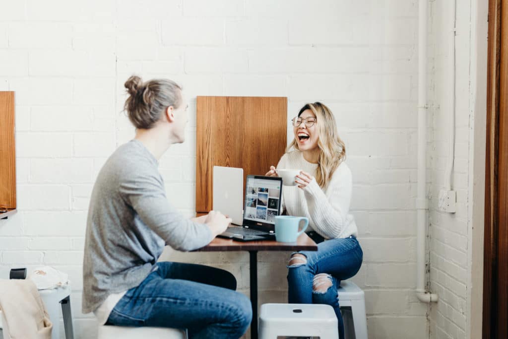 Man and woman laughing at laptop