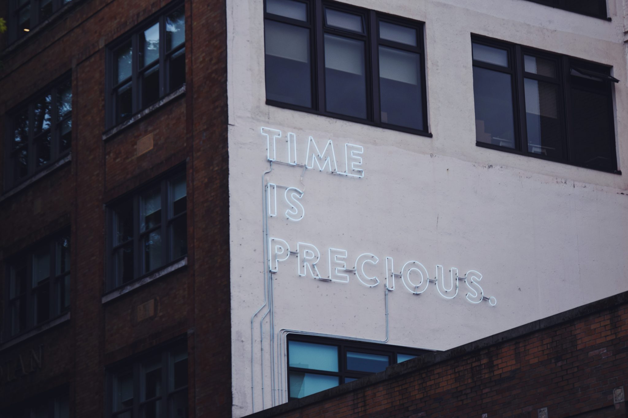 The words "Time is precious" in lights on the side of a building