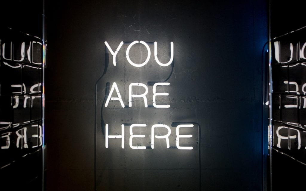 "You are here" written in lights and reflected onto two walls