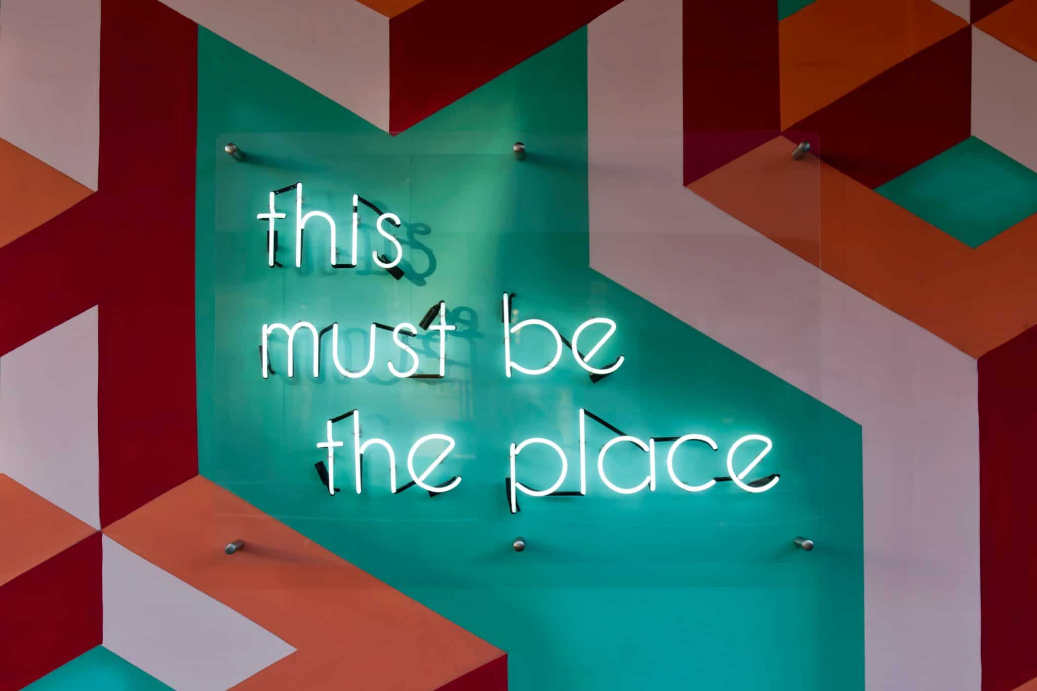 "This must be the place" written in lights on an artistic modernist patterned wall
